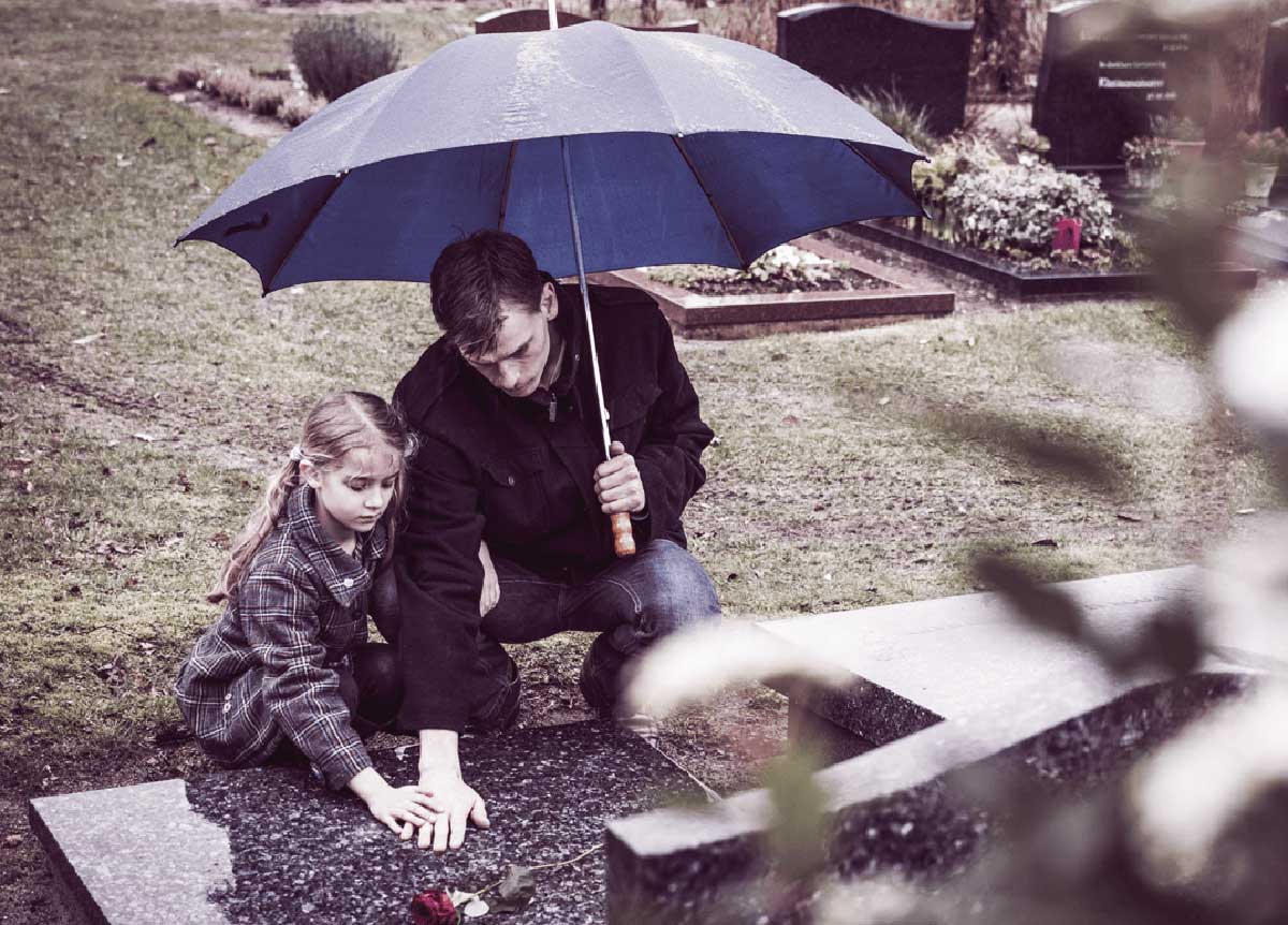 Niña y su padre en un cementerio